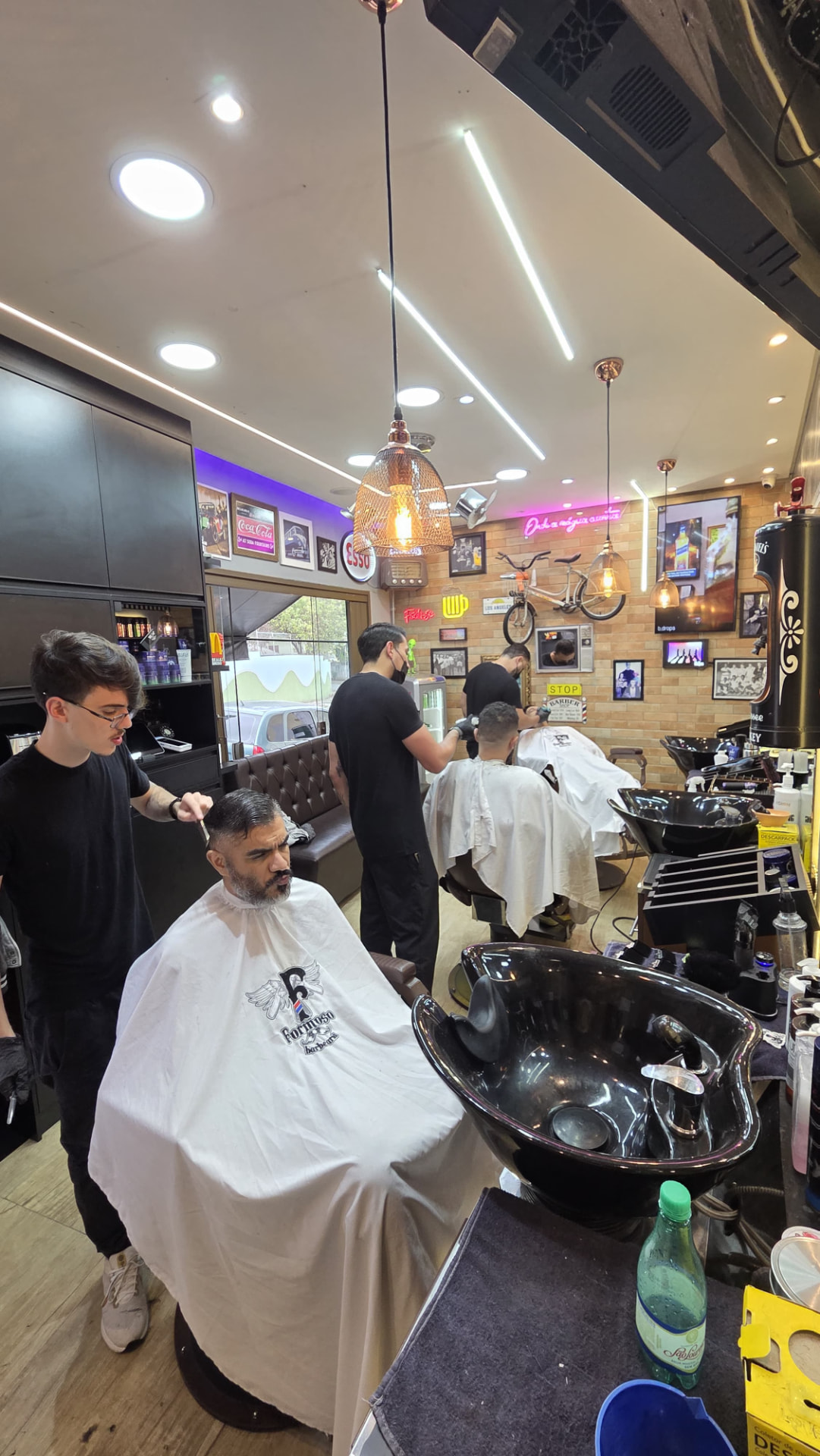 Salão da Barbearia Formoso com tijolinho aparente e luminárias de cobre
